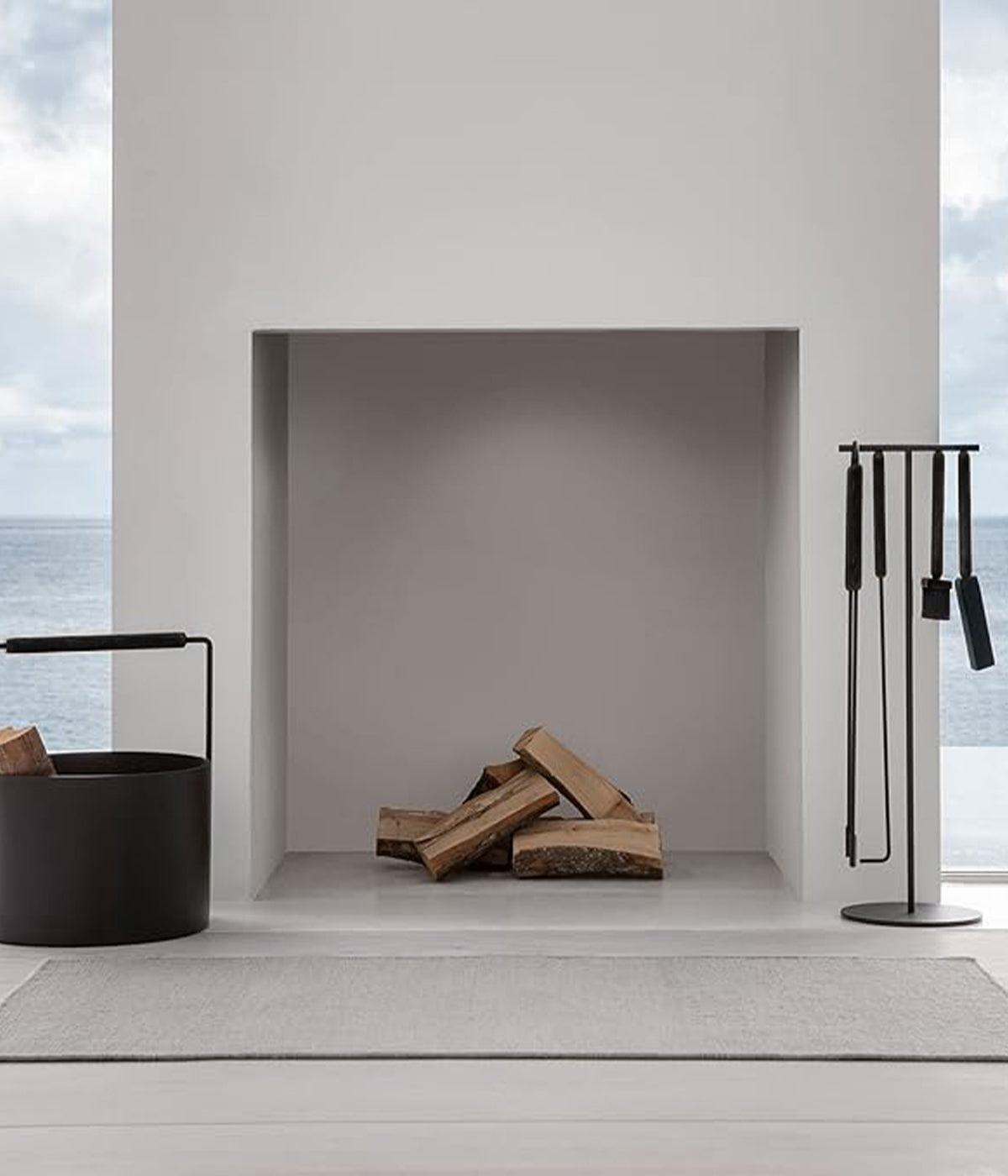 Kaschkasch-designed fireplace tool set and log holder in front of a hearth