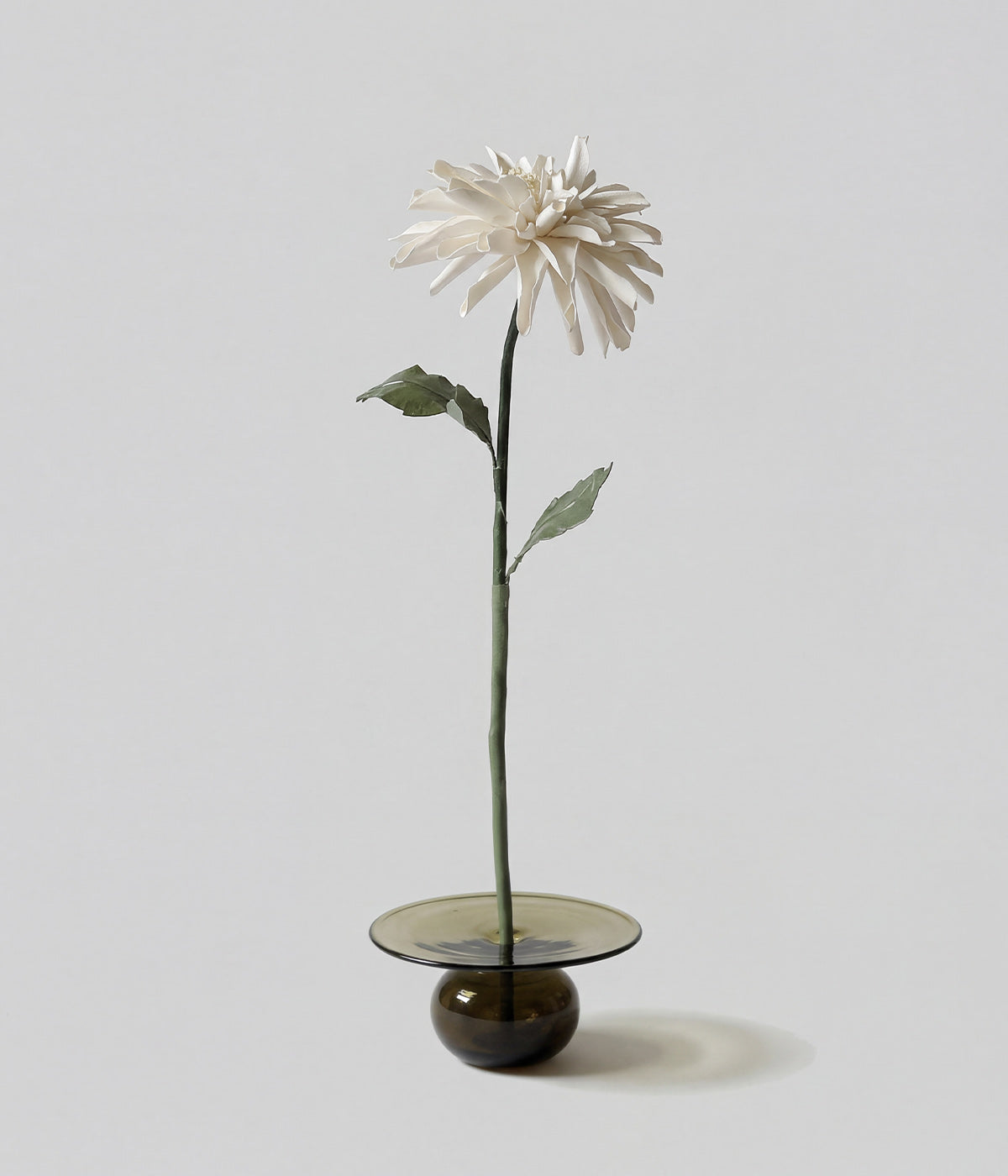 Wax-coated paper chrysanthemum flower in a small glass base