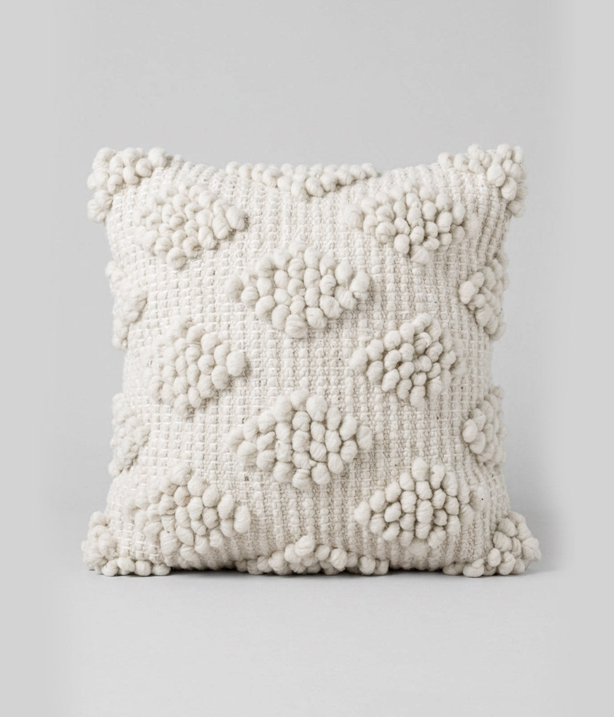 Cream throw pillows with handwoven diamond bobble texture
