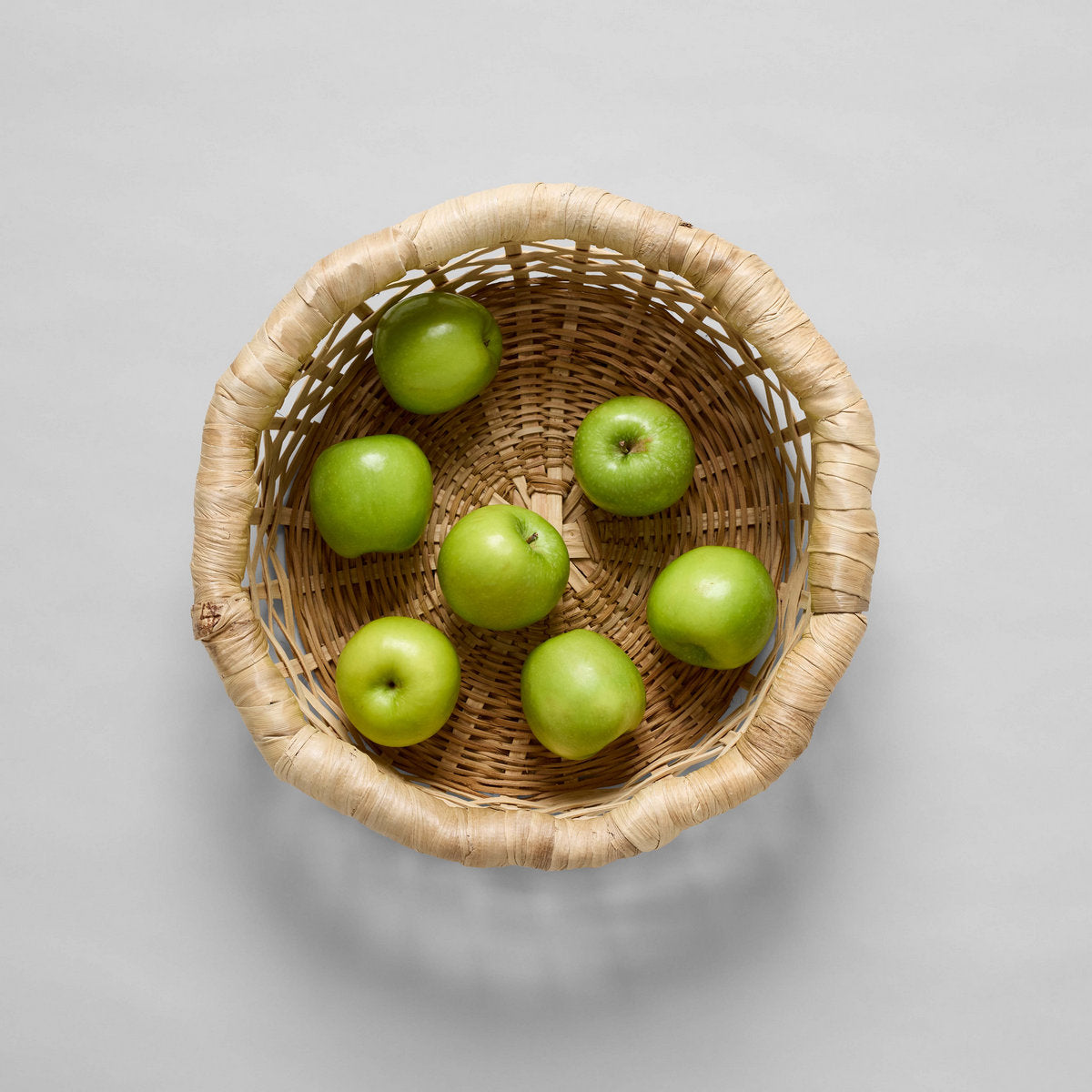 Top view of woven basket filled with green apples