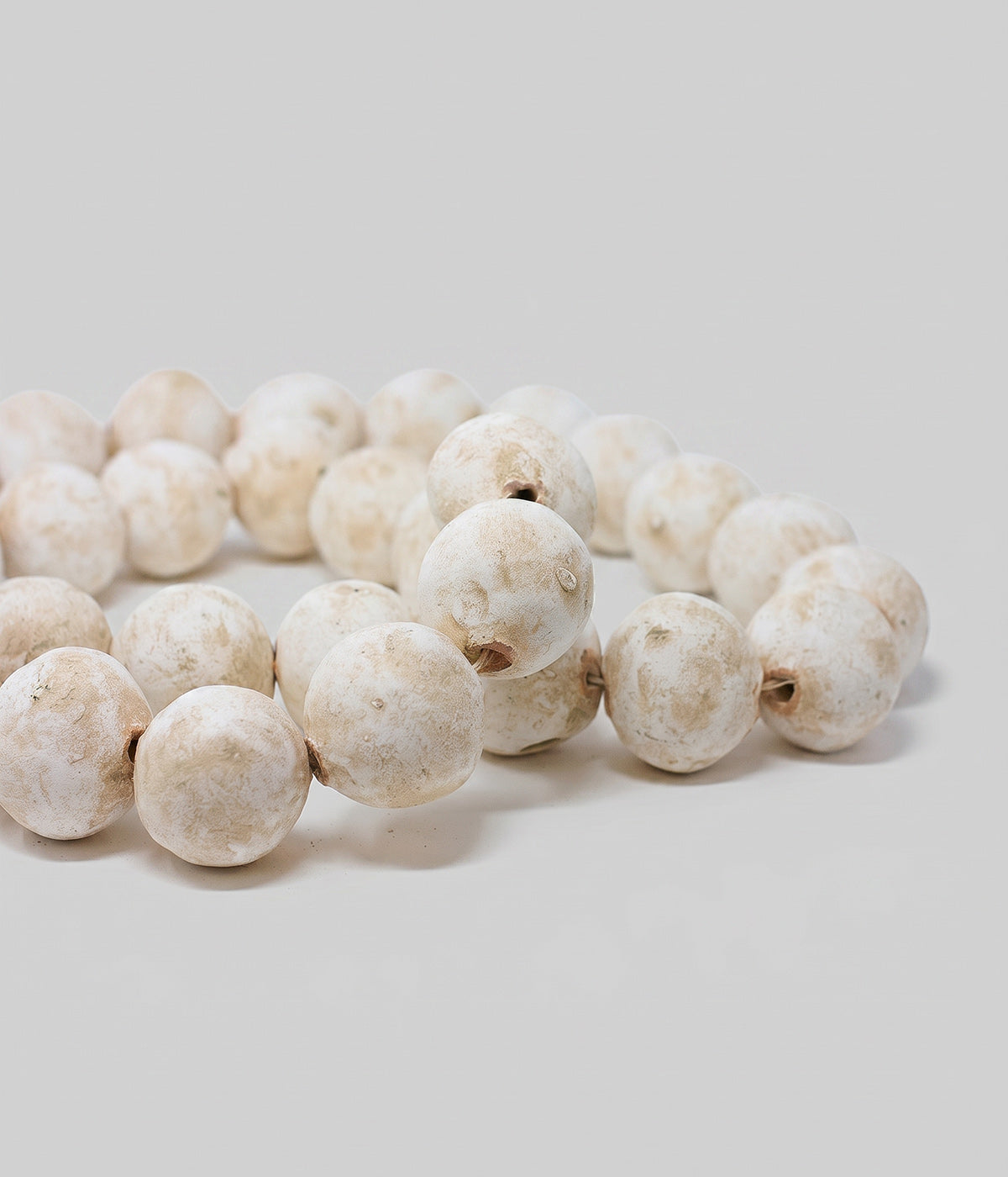 Decorative bead strand with white patina finish and exposed clay details