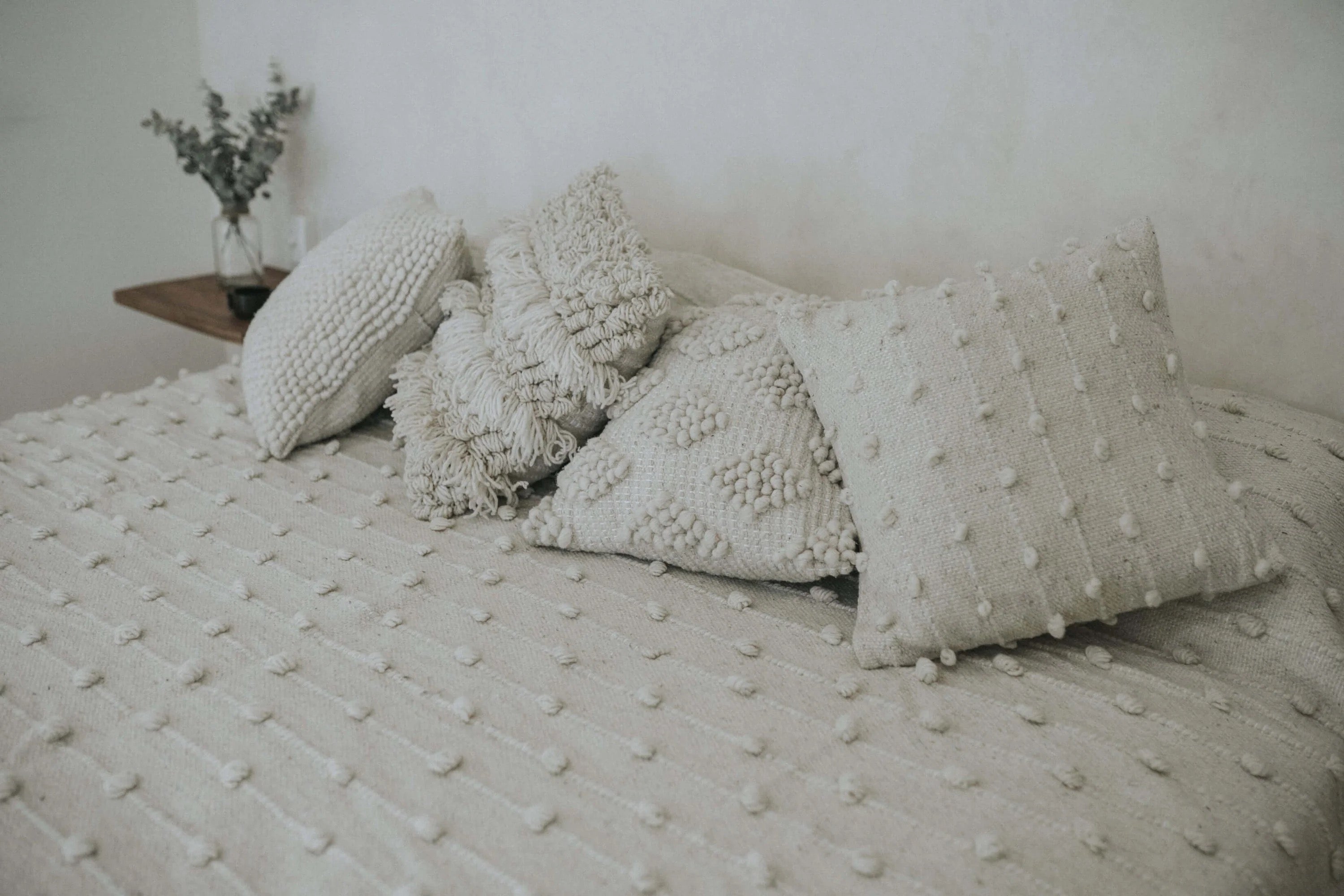 A cozy bed styled with textured square throw pillows
