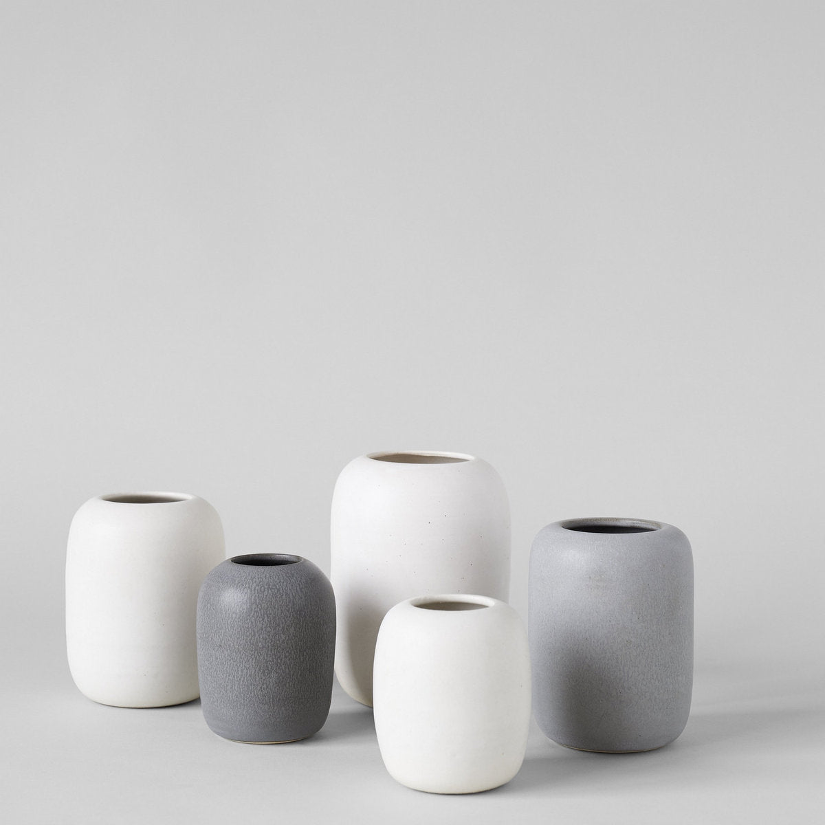 Group of white and grey stoneware vases in varying sizes with rounded shapes