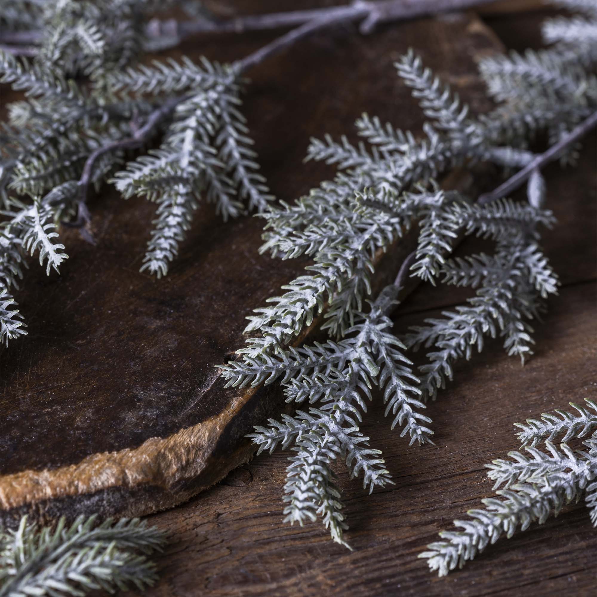 Artificial winter greenery with soft frosted pine needles and layered sculptural shape
